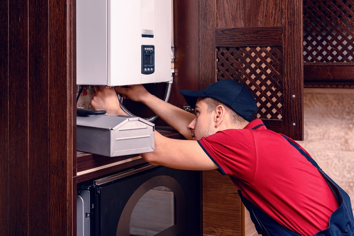 A young skilled worker regulates the gas boiler before use