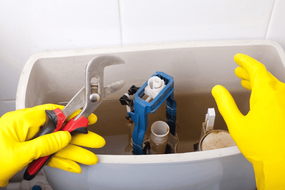 Plumber repairing toilet cistern at water