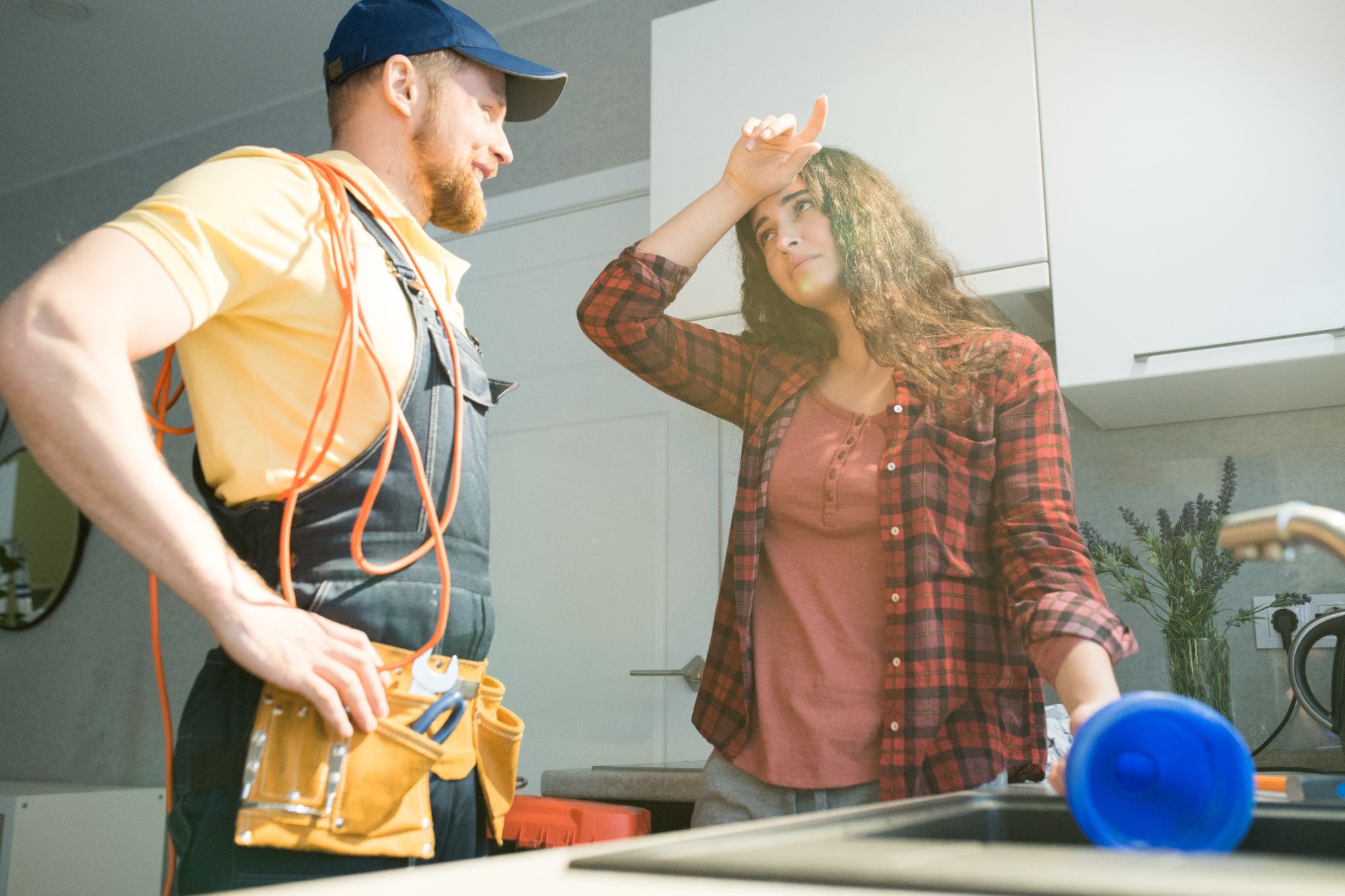young woman holding plunder while talking to plumber