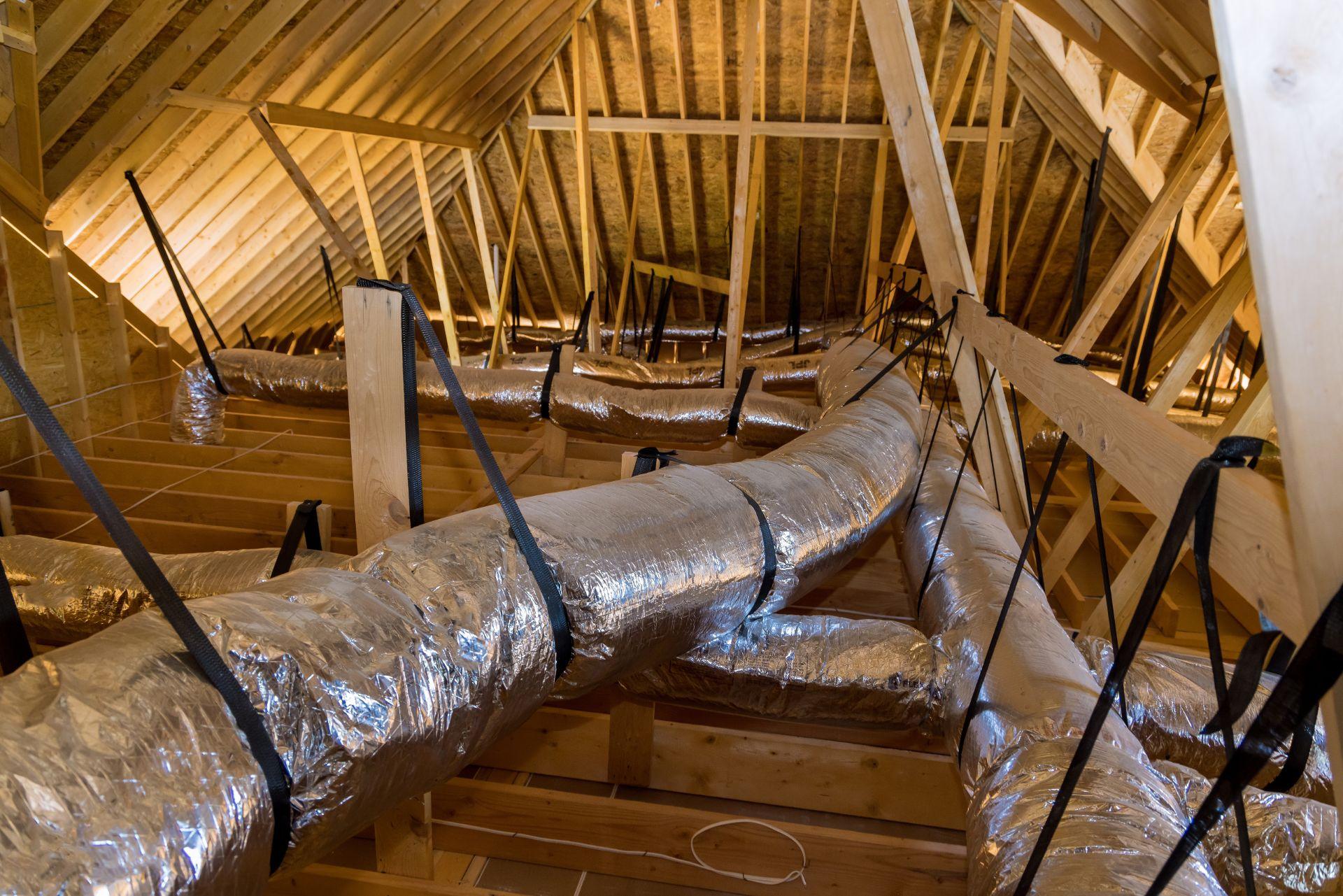 Home under construction ventilation pipes are silver insulation material on ceiling of attic
