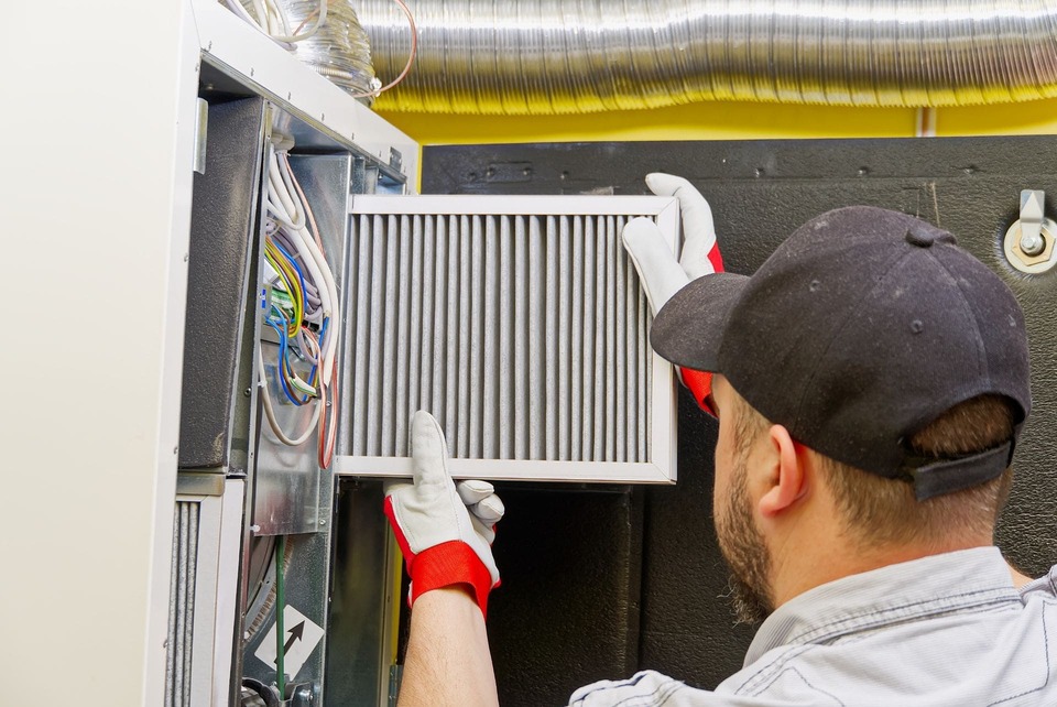 HVAC service technician changing dirty air filter in the central ventilation system.