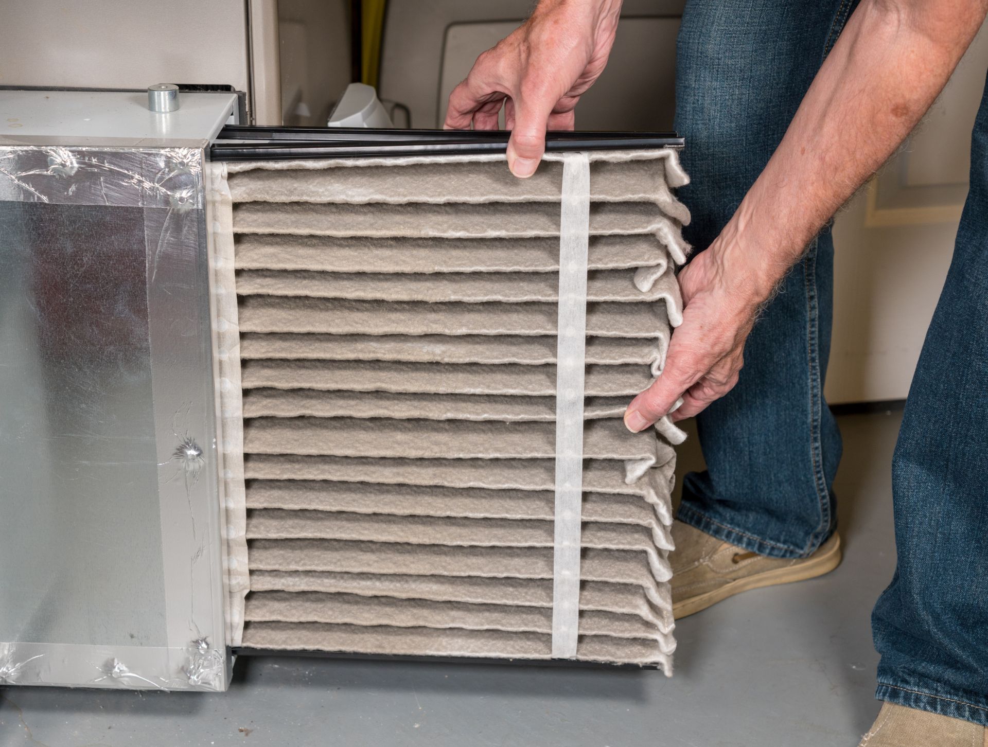 Man changing a dirty air filter in a HVAC Furnace