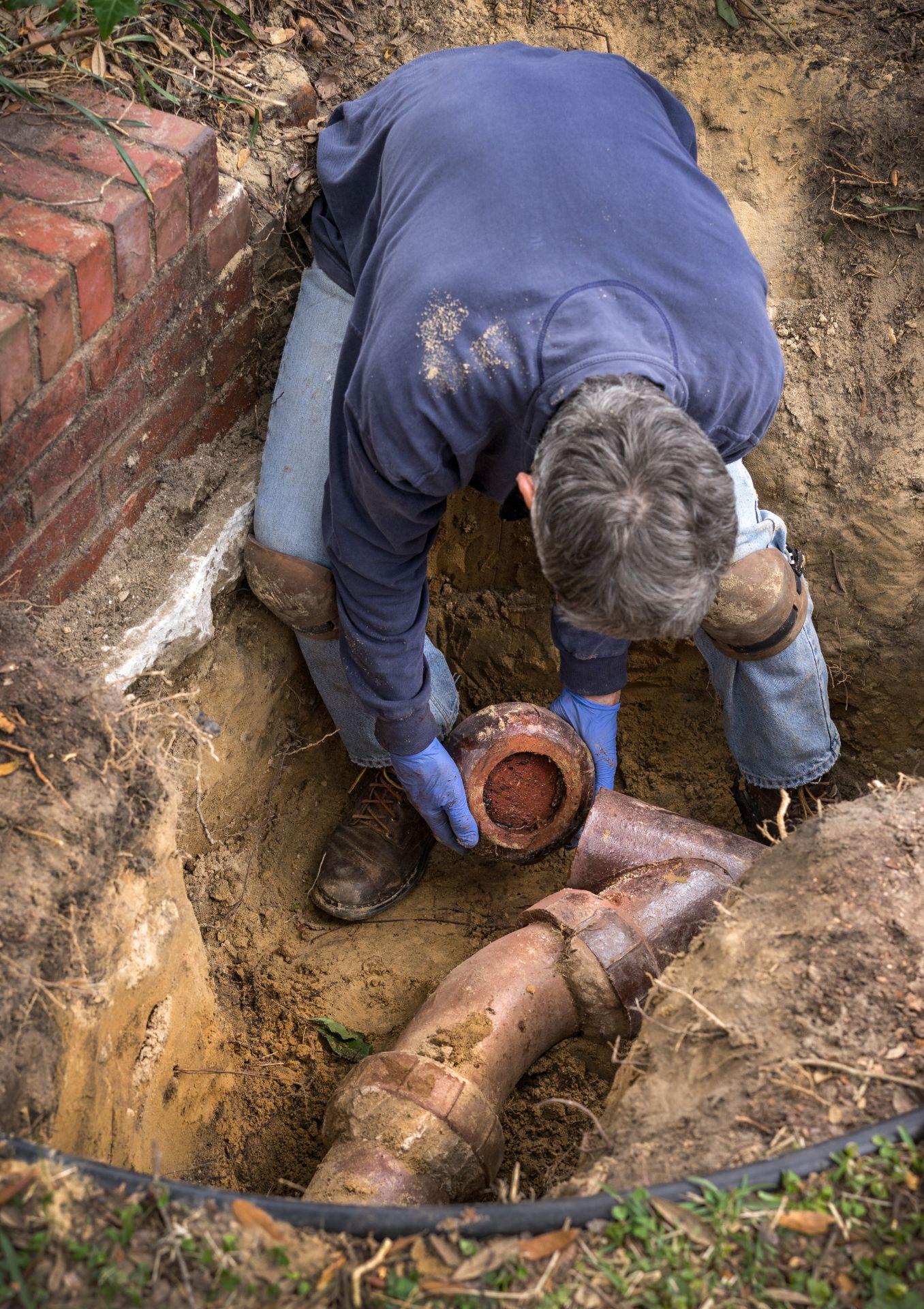 Plumber working on old clay ceramic sewer line pipes